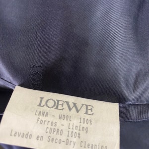 May include: A white tag with black text that reads "LOEWE", "LANA - WOOL 100%", "Forros - Lining", "CUPRO 100%", and "Lavado en Seco-Dry Cleaning".