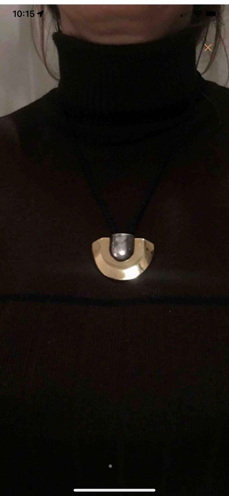 May include: A black necklace with a gold and silver pendant shaped like a crescent moon.