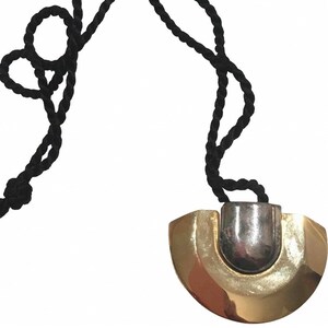 May include: A gold and silver pendant necklace with a black cord. The pendant is a half-circle shape with a silver center.