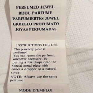 May include: A white label with black text that reads "LA NUIT de paco rabanne" and instructions for use for a perfumed jewel. The text reads "PERFUMED JEWEL, BIJOU PARFUME, PARF&Uuml;MIERTES JUWEL, GIOIELLO PROFUMATO, JOYAS PERFUMADAS". The instructions for use are in English and French.