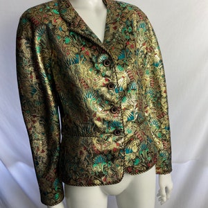 May include: A gold blazer with a colorful floral pattern. The blazer has a v-neck, long sleeves, and a button closure.