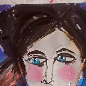 以下が含まれることがあります： 青い目をした女性の顔の絵。頬はピンクで、髪は黒。背景は濃い青色です。