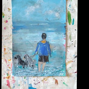 K&ouml;nnte beinhalten: Ein &Ouml;lgem&auml;lde auf Papier, das eine Person mit blauer Kapuzenjacke und dunkler kurzer Hose zeigt, die im flachen Meerwasser steht. Zwei Hunde sind an Leinen neben der Person. Die Szene zeigt einen hellblauen Himmel und strukturiertes Wasser.