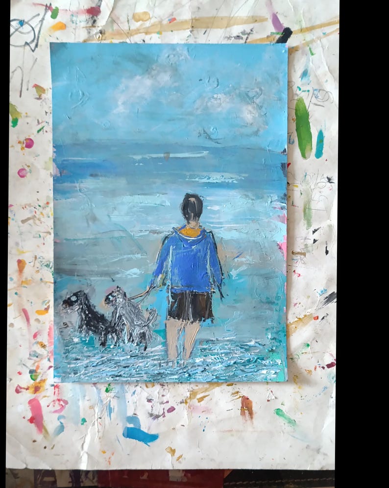 K&ouml;nnte beinhalten: Ein &Ouml;lgem&auml;lde auf Papier, das eine Person mit blauer Kapuzenjacke und dunkler kurzer Hose zeigt, die im flachen Meerwasser steht. Zwei Hunde sind an Leinen neben der Person. Die Szene zeigt einen hellblauen Himmel und strukturiertes Wasser.