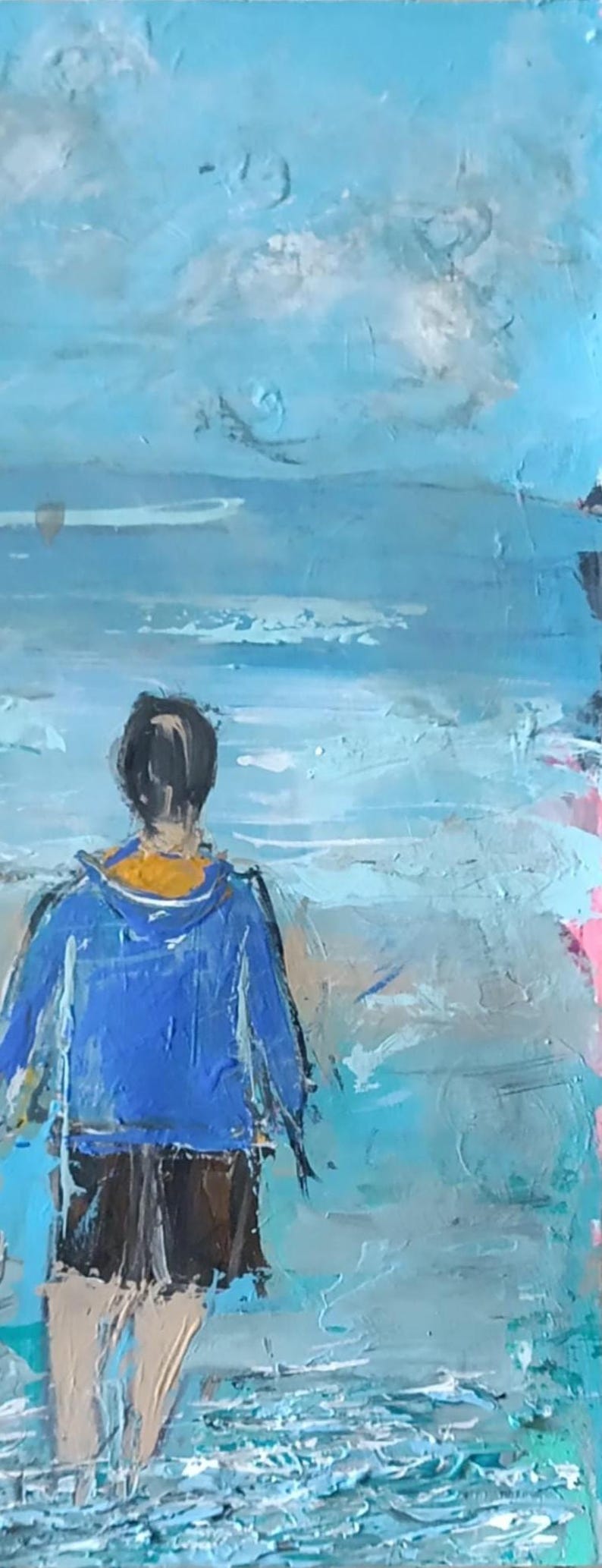 K&ouml;nnte beinhalten: Ein &Ouml;lgem&auml;lde auf Leinwand, das eine Person von hinten zeigt, die im flachen Wasser am Strand steht. Die Person tr&auml;gt eine leuchtend blaue Kapuzenjacke mit gelbem Innenfutter und eine dunkle Shorts. Die Szene zeigt texturierte blaue Meereswellen.