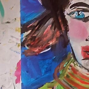 以下が含まれることがあります： 黒髪碧眼の女性の絵。彼女は赤色のアクセントがついたカラフルなストライプのセーターを着ています。背景は青と紫の抽象的なデザインです。