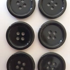 May include: Six black plastic buttons, each with four holes. The buttons are round and have a smooth, glossy finish.