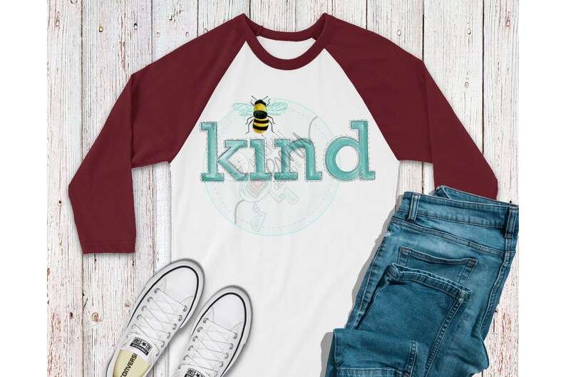 May include: A white and maroon baseball tee shirt with a bee and the word "kind" in teal blue lettering.