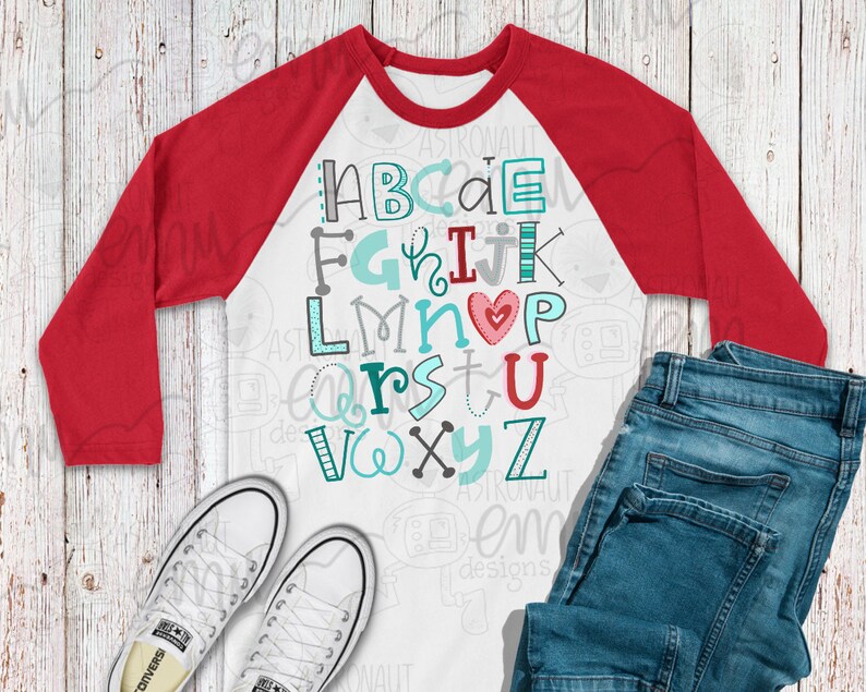 May include: A white and red baseball tee shirt with a colorful alphabet design. The letters are in different fonts and colors, with a red heart in the center. The shirt has a white front and red sleeves.
