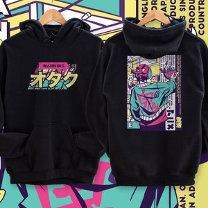 May include: Black hooded sweatshirt with a graphic print of a cartoon character with red and pink hair and a green jacket. The text "WARNING オタク" is printed on the front of the sweatshirt.
