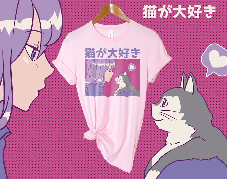 Puede incluir: Camiseta rosa con un gr&aacute;fico de una chica y un gato con el texto japon&eacute;s "猫が大好き" (que significa "Me encantan los gatos") impreso en ella.