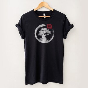 Puede incluir: Camiseta negra con un gr&aacute;fico blanco de un &aacute;rbol en un c&iacute;rculo con la palabra japonesa "Zen" en rojo.