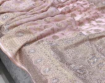May include: A pink chiffon saree with a gold and silver embroidered border. The saree has a floral pattern and is decorated with sequins and beads.
