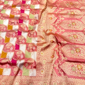 May include: A pink fabric textile featuring a woven pattern of gold, white, lime green, and magenta squares. The fabric includes intricate gold metallic floral motifs and a wide decorative border with repeating botanical designs and ornate patterns.