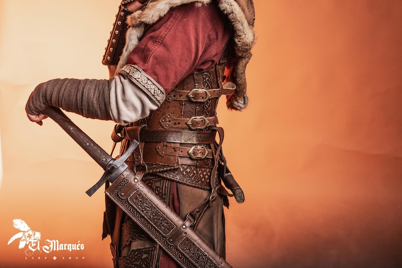 May include: A person wearing a brown leather and metal armor with a sword strapped to their side. The armor is decorated with intricate designs and has a fur collar.