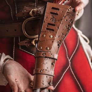 Puede incluir: Una funda de cuero marr&oacute;n con una hebilla de metal y un dise&ntilde;o decorativo. La funda contiene una peque&ntilde;a pistola de madera marr&oacute;n.