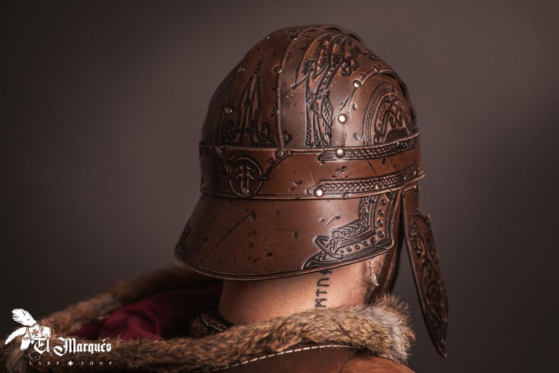 K&ouml;nnte beinhalten: Brauner Lederhelm mit aufwendigen gepr&auml;gten Designs, Nieten und einem Visier. Der Helm weist dekorative Muster auf und ist Teil eines Kost&uuml;ms oder einer historischen Nachstellung. Das Bild zeigt die R&uuml;ckseite des Helms.