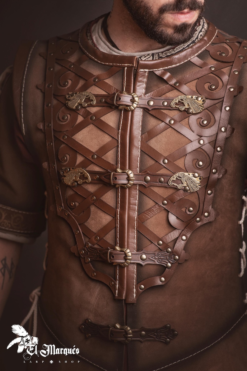 Peut inclure: Une armure de poitrine en cuir marron avec des croisillons complexes et des fermoirs m&eacute;talliques d&eacute;coratifs. L'armure pr&eacute;sente des d&eacute;tails orn&eacute;s, notamment des motifs en relief et des rivets. La conception comprend une fermeture &eacute;clair centrale et des accents m&eacute;talliques d&eacute;coratifs.