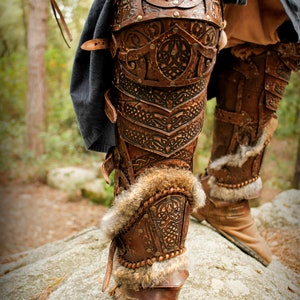 May include: Close-up of a pair of brown leather knee-high boots with intricate designs and fur trim. The boots are worn and have a rustic look.