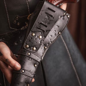Puede incluir: Una funda de cuero negra con un dise&ntilde;o decorativo y detalles met&aacute;licos. La funda est&aacute; dise&ntilde;ada para sostener una pistola.