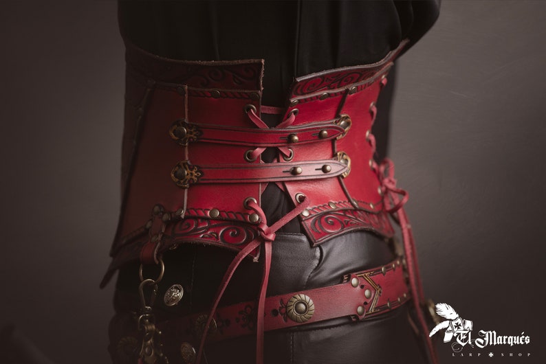 K&ouml;nnte beinhalten: Ein rotes Lederkorsett mit aufwendigen floralen Designs und Metallverzierungen. Das Korsett ist hinten geschn&uuml;rt und hat vorne eine dekorative Schnalle.