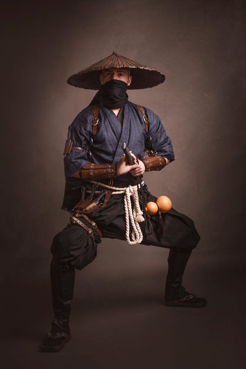 May include: A person wearing a blue and brown costume with a wide-brimmed hat, holding a sword and standing in a fighting pose.