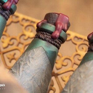 May include: Three green glass bottles with a textured surface and a brown rope around the neck. Each bottle has a red wax seal on the top.