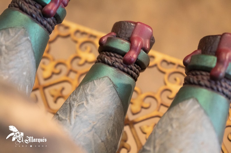 May include: Three green glass bottles with a textured surface and a brown rope around the neck. Each bottle has a red wax seal on the top.