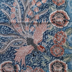 May include: A patterned textile with a central bird motif, rendered in red, black, and white against a dark blue backdrop. The design incorporates floral and leaf elements, with prominent, detailed flowers. The overall style suggests a traditional craft.