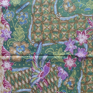 May include: Green fabric with a repeating pattern of flowers, birds, and a geometric design. The fabric has a brown and gold woven pattern. The text "NY TIDA SIANG CWAI" is visible in the top left corner.