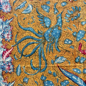Könnte beinhalten: Ein blauer und goldener Batikstoff mit einem Pfauenmuster. Der Stoff hat ein Blumenmuster mit roten, weißen und blauen Akzenten. Der Text "H.T. JAH DUKUH RAT SOLO" ist in der oberen linken Ecke gedruckt.