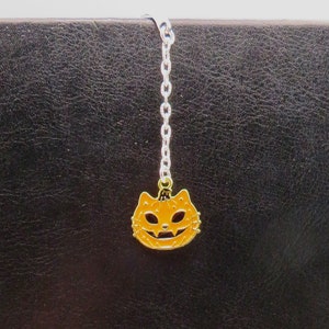 May include: A black leather-bound journal with a silver chain bookmark featuring a gold cat head charm.