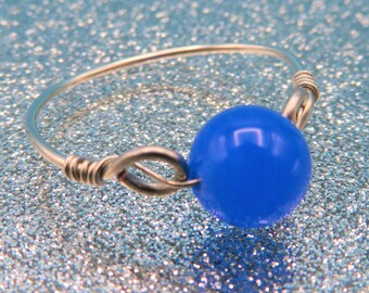 May include: A silver wire ring with a bright blue glass bead.