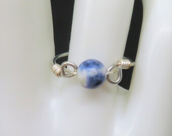 May include: A silver wire ring with a blue and white gemstone bead.