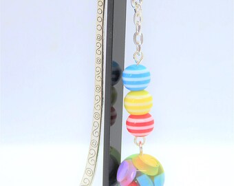 May include: Silver bookmark with a chain and colorful striped and patterned beads. The bookmark has a decorative design on the metal.
