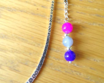 May include: Silver bookmark with a decorative swirl design and three beads. The beads are pink, light blue, and purple.