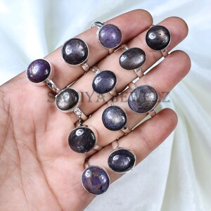 May include: A collection of silver rings with dark purple gemstones. The rings are arranged on a hand, showcasing the different styles and sizes of the stones.