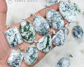 May include: A collection of silver-toned pendants with various shapes, featuring white and green moss agate stones. The pendants have a polished finish and are displayed on a soft, white surface. The pendants are ready to be worn as jewelry.