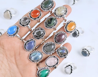 May include: A collection of gemstone rings with silver bands. The rings feature various oval and rectangular stones in shades of blue, green, orange, and pink. Each ring has a decorative, floral-inspired setting.