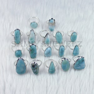 May include: A collection of 16 silver rings with blue-green gemstone settings. The rings feature a variety of shapes and sizes of gemstones, including oval, round, and teardrop.