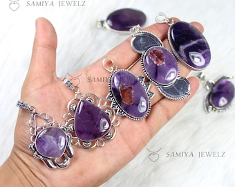 May include: A collection of amethyst pendants in various shapes and silver settings. The pendants feature deep purple stones with unique patterns and textures. The image includes the text "SAMIYA JEWELZ".