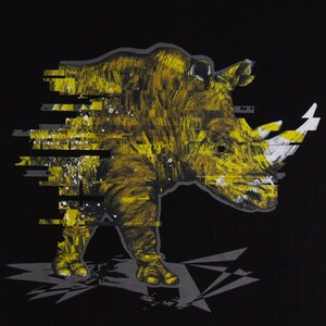 May include: A black t-shirt with a yellow and white graphic print of a rhinoceros with a pixelated effect. The rhinoceros is facing the left side of the image. The text "Born Hybrid" is printed on the top left corner of the shirt.