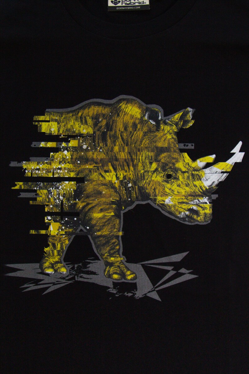 May include: A black t-shirt with a yellow and white graphic print of a rhinoceros with a pixelated effect. The rhinoceros is facing the left side of the image. The text "Born Hybrid" is printed on the top left corner of the shirt.