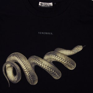 May include: Black t-shirt featuring a graphic of a black snake with the text "VENEMOUS." and "BLACK SNAKE, Pseudechis porphyriacus. Born Hybrid."