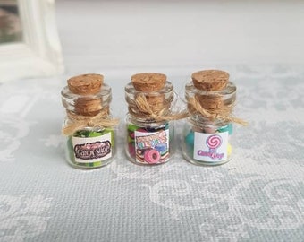 May include: Three small glass jars with cork lids and twine tied around the necks. Each jar is filled with colorful candy and has a label that says "Candy Shop".