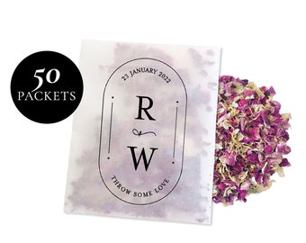May include: A white paper bag with a black and white label that says "23 January 2022", "R & W", "Throw Some Love", and "50 Packets". The bag is filled with pink and white rose petals.