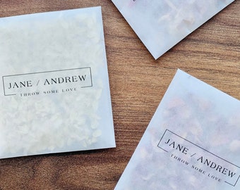 May include: Four white paper bags filled with confetti. Each bag has a black and white label with the text "Jane / Andrew - Throw some love".
