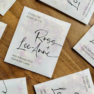 May include: White paper bags with a watercolor design and black text. The text reads "Throw Some Love" and "Ross + Lee-Anne" with the date "26th February 2022" and the location "Glenskirlie Castle".