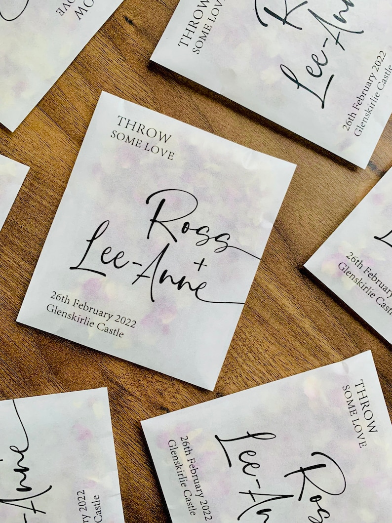 May include: White paper bags with a watercolor design and black text. The text reads "Throw Some Love" and "Ross + Lee-Anne" with the date "26th February 2022" and the location "Glenskirlie Castle".