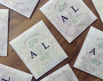 May include: White paper bags with a green leafy design and the text "AARON & LAURA" and "AL" with the date "04.03.22".